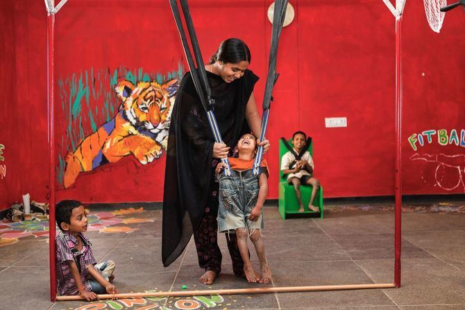 La exposición 'Tierra de Sueños' se podrá visitar desde el 25 de enero hasta el 23 de febrero, en la plaza del Pueblo, de Alcobendas, de forma gratuita. En la imagen, una cuidadora ayuda a unos niños a practicar ejercicios para mejorar su movilidad en el Centro de Parálisis Cerebral de Bathalapalli.