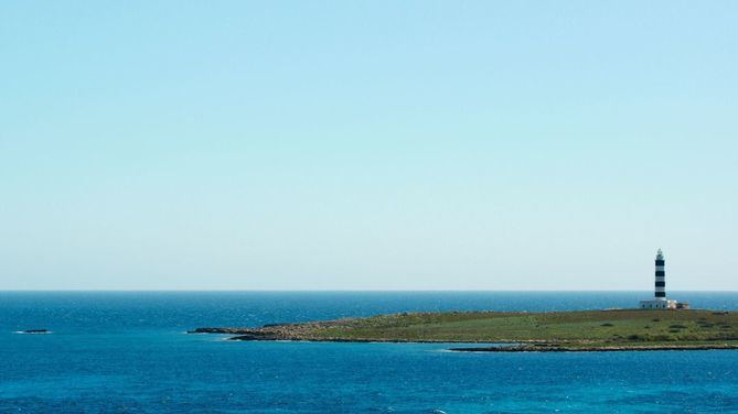 El más alto de todos los faros de Menorca se erige en un islote deshabitado, que se encuentra en el extremo sureste de la isla. L’Illa de l’Aire es uno de los rincones más especiales de Menorca y, probablemente, el faro de más difícil acceso. 