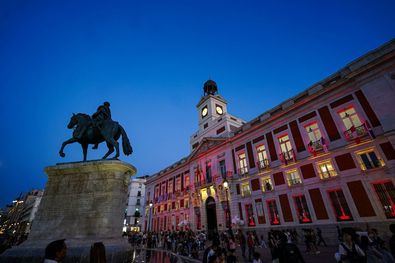 El emblemático edificio de la madrileña Puerta del Sol que se engalanará con las luces extraordinarias rojo y gualda, luce, además, en sus balcones las 22 enseñas nacionales de los países hispanohablantes.