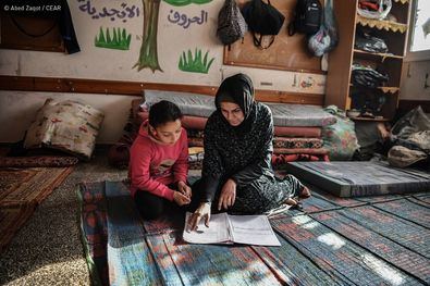 En un aula de UNRWA, una madre enseña a su hija después de que la clase se convirtiera en un refugio para ellas y otras familias. 16 de enero de 2024