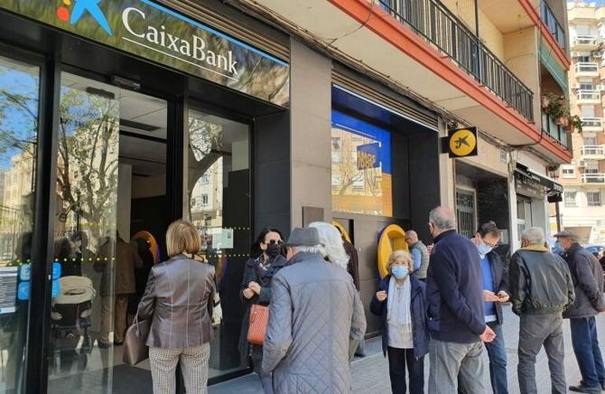 El lugar de la concentración vecinal se halla entre las oficinas de CaixaBank y el Banco Santander, dos establecimientos que a diario generan en la calle largas colas de espera.